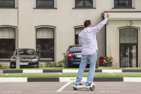 Business man riding an electronic scooter outdoors - personal portable eco transport, hover board,...