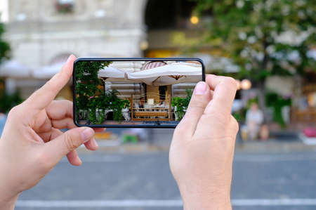 Man hold smartphone with modern cafe on itのeditorial素材