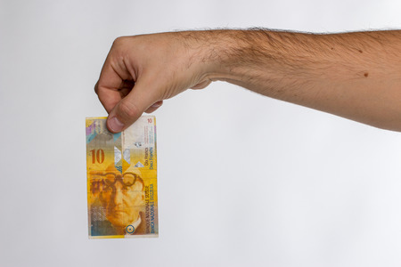 Man hold 10 swiss franc banknote in hand. Isolated on white