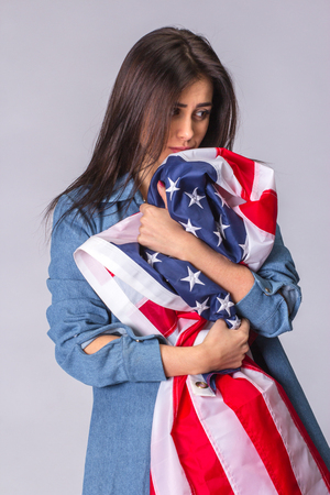 Flag of United States of America in hands of sad beautiful woman. Isolated on white.の写真素材