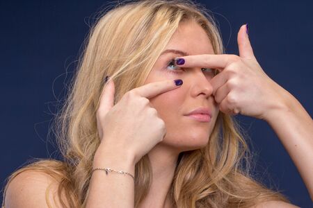 Blond woman  inserting contact lensesの写真素材