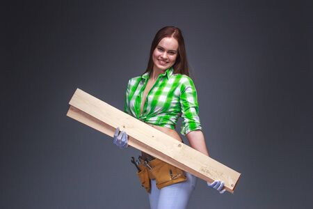 Pretty carpenter worker carrying wooden boards on armの写真素材