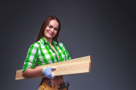 Pretty carpenter worker carrying wooden boards on armの写真素材