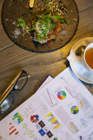 Business brekfast. Set of food, drinks and abstract business papers on the table.の写真素材