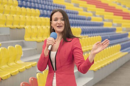 Pretty journalist is reporting from the stadium for televisionの写真素材