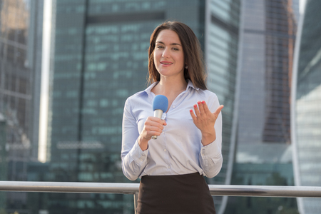 Professional microphone in the hands of an attractive reporter girl working in the background of a business centerの写真素材