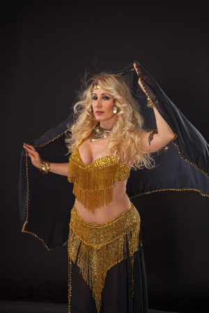 Attractive blond woman in golden dress on black background.の写真素材