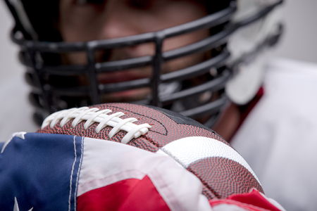 American football ball with the national flag with defocused player on background.の写真素材