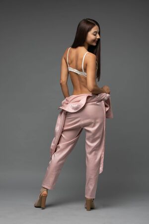 Woman in beautiful lingerie takes off her jumpsuit in studioの写真素材