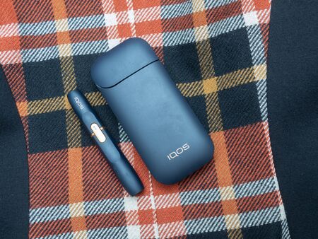 Iqos Electronic Cigarette With Heat-Not-Burn System in modern textille background