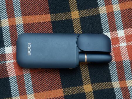 Iqos Electronic Cigarette With Heat-Not-Burn System in modern textille background