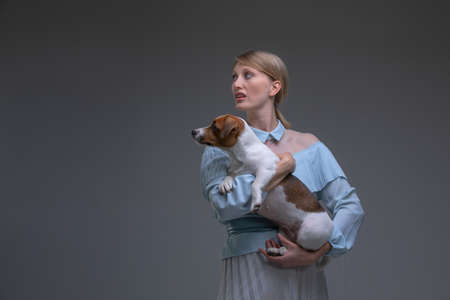 Blond Housewife in vintage dress holds jack russell dog