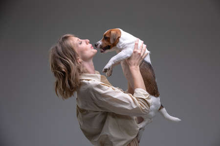 Pretty woman holds jack russell terrier puppy in front of her faceの写真素材