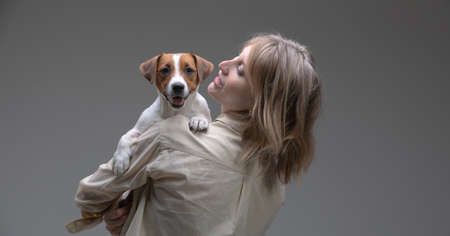 Pretty woman holds jack russell terrier puppy on her shoulder