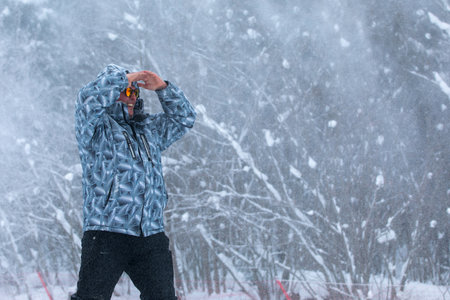 Man stands alone against white snowstorm and snow storm, a snowfall outdoors.の写真素材