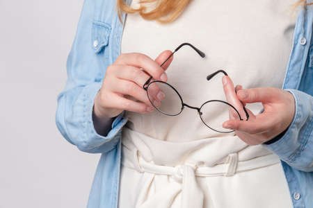 Ginger woman Holds glasses in handsの写真素材