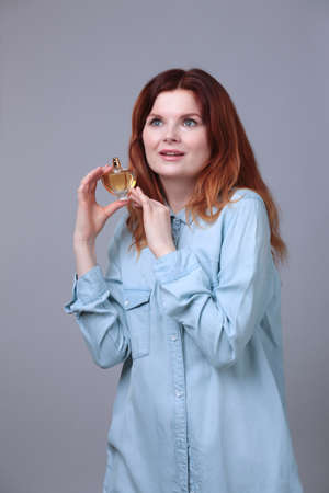 Perfume bottle in hands of woman wearing blue jeans wear