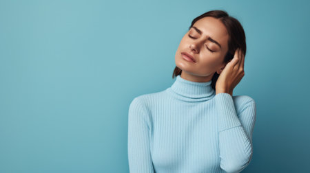 Portrait of attractive tired upset unhealthy woman standing massaging neck to relieve pain, muscle strain in back, isolated on blue background.の素材