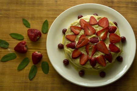 Creamy white cake with strawberry pieces and mint leaves.の写真素材
