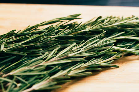 bundle of sprigs of rosemary on a wooden light background.の写真素材