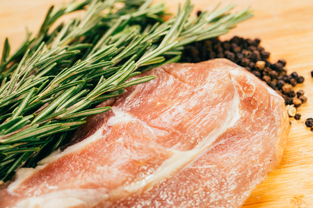 raw meat, sprig of rosemary and pepper on a wooden light background.の写真素材