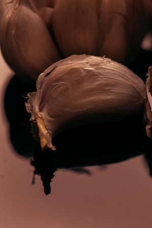 clove of garlic close-up on a dark mirror background.