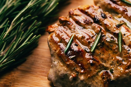 grilled meat, sprig of rosemary and red hot pepper on a wooden light background.の写真素材
