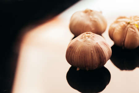 several heads of garlic on a dark mirror background.の写真素材