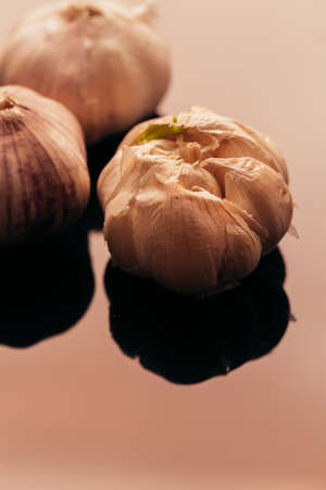 several heads of garlic on a dark mirror background.の写真素材