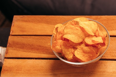 clear bowl of potato chips on a wooden background.の写真素材