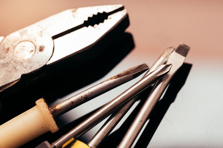many different screwdrivers and pliers on a dark background bunch.