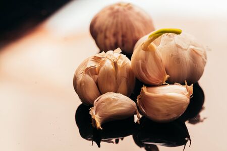 several heads of garlic on a dark mirror background.