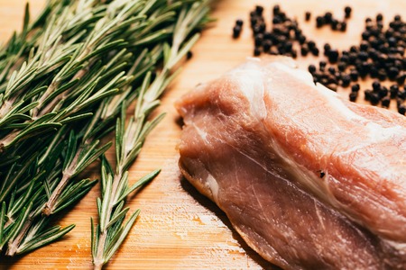 raw meat, sprig of rosemary and pepper on a wooden light background.の写真素材
