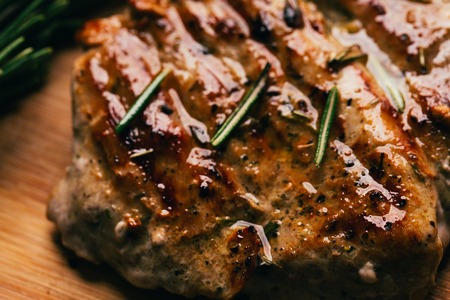 grilled meat, sprig of rosemary and red hot pepper on a wooden light background.の写真素材