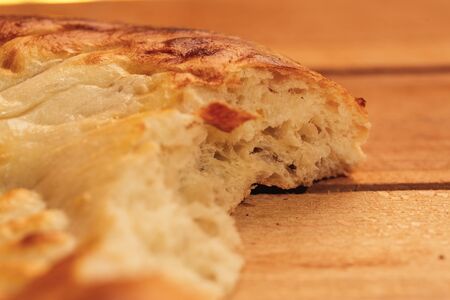 National Uzbek bread bitten on a wooden background, close-up.の写真素材