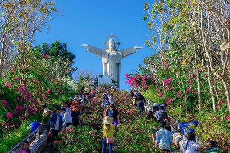 Vung Tau, Vietnam - February 21, 2018: Statue of Jesus Christ and many tourists walking in the park...