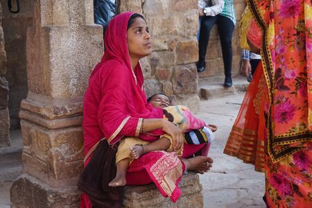 Delhi, India - October 28, 2017: Poor Indian woman sitting with a babyのeditorial素材