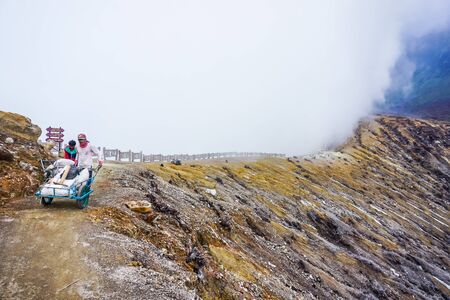 Ijen Volcano, Indonesia - April 1, 2018: Workers mine sulfur from the crater of the volcano