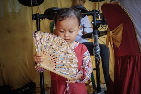 West Java, Indonesia - April 12, 2018: Little Indonesian girl plays with a fanのeditorial素材