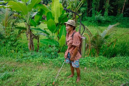 West Java, Indonesia - April 12, 2018: A man with a home-made machine for spraying plants from harmful insects.のeditorial素材