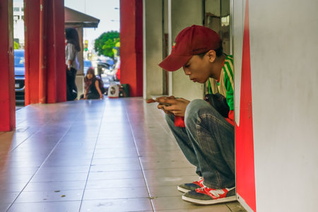 Kota Bharu, Malaysia - April 6, 2019: The guy is hanging on the phone on the street of the cityのeditorial素材