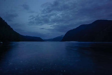Beautiful Sayan mountains in the reflection of the Yenisei river at sunset