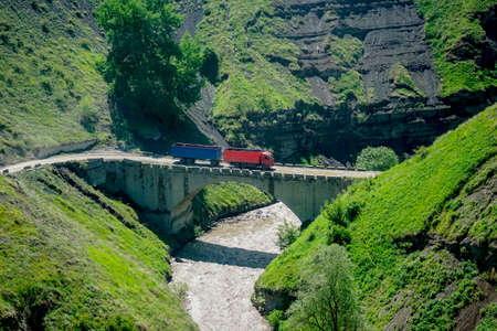 Truck rides over the bridge over the mountain riverの写真素材