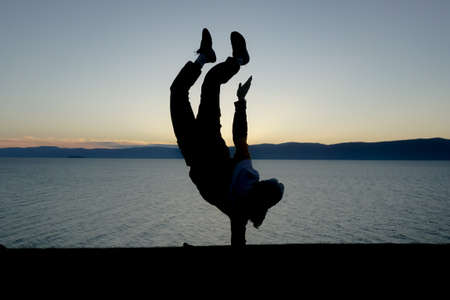 Silhouette of a man doing acrobatic exercises in nature in Baikalの写真素材