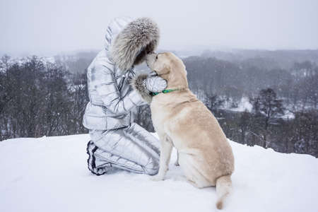 Girl with a white dog in the snow in winterの写真素材