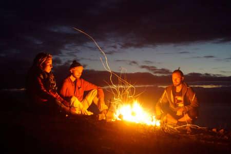 Olkhon Island, Russia - September 7, 2020: Travelers warm themselves by the fire at night