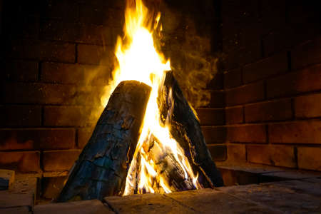Bright warm fire in a brick fireplace in the houseの写真素材