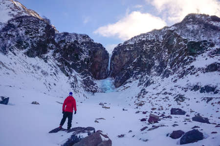 A traveler at the frozen Vilyuchinsky waterfall in Kamchatka peninsulaの写真素材