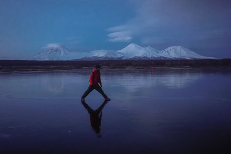 A Man on a Frozen Lake with a View of Volcanoes at sunset