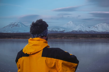 A Man on a Frozen Lake with a View of Kamchatka Volcanoes at sunsetの写真素材